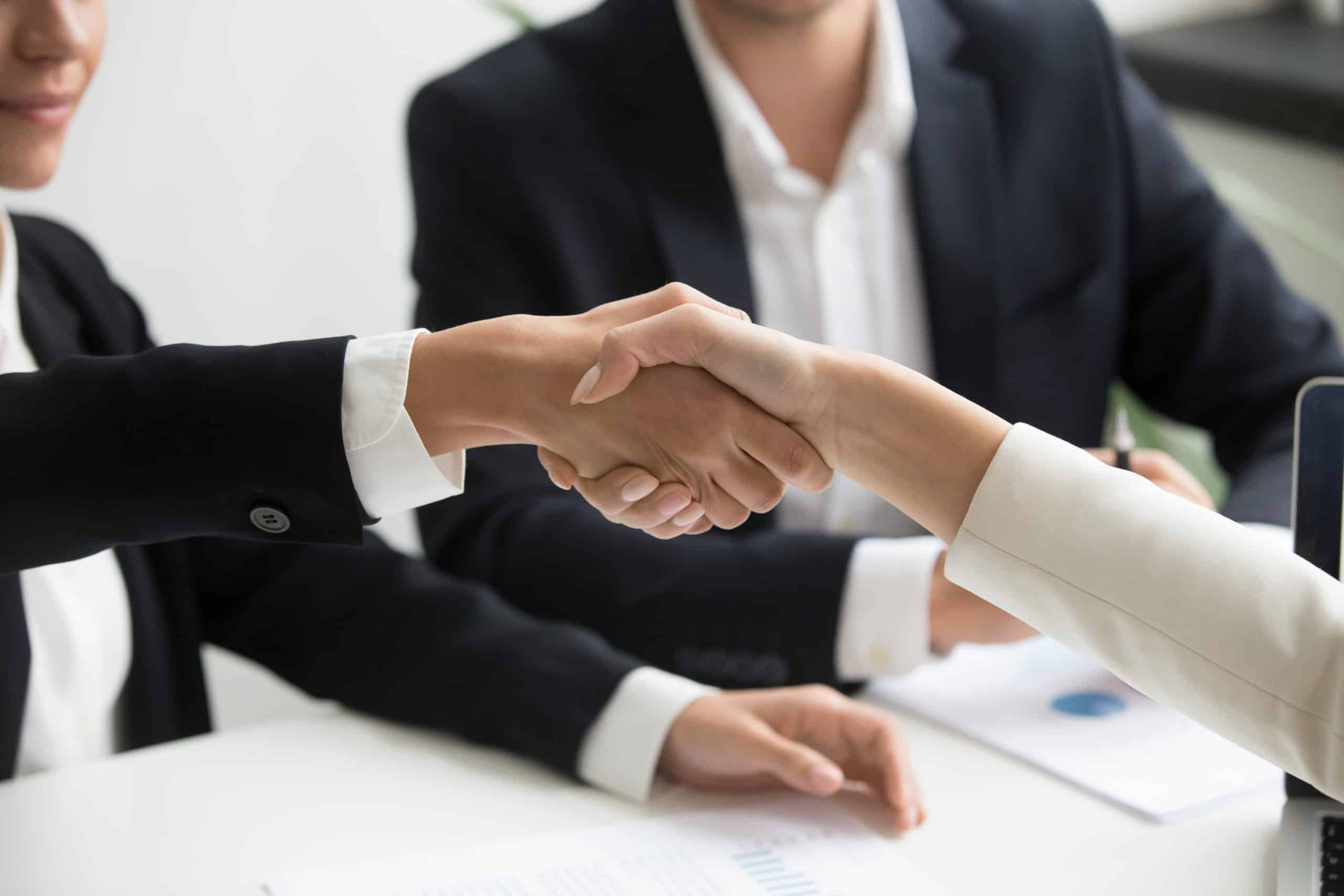 female hands shaking at group meeting making partnership deal closeup scaled