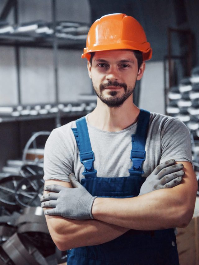 cropped portrait of a young worker in a hard hat at a large metalworking plant scaled 1