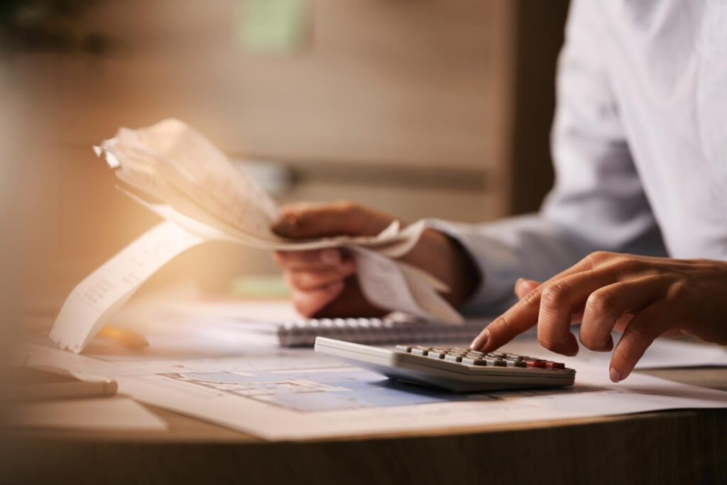 closeup de economista usando calculadora ao passar por contas e impostos no escritorio