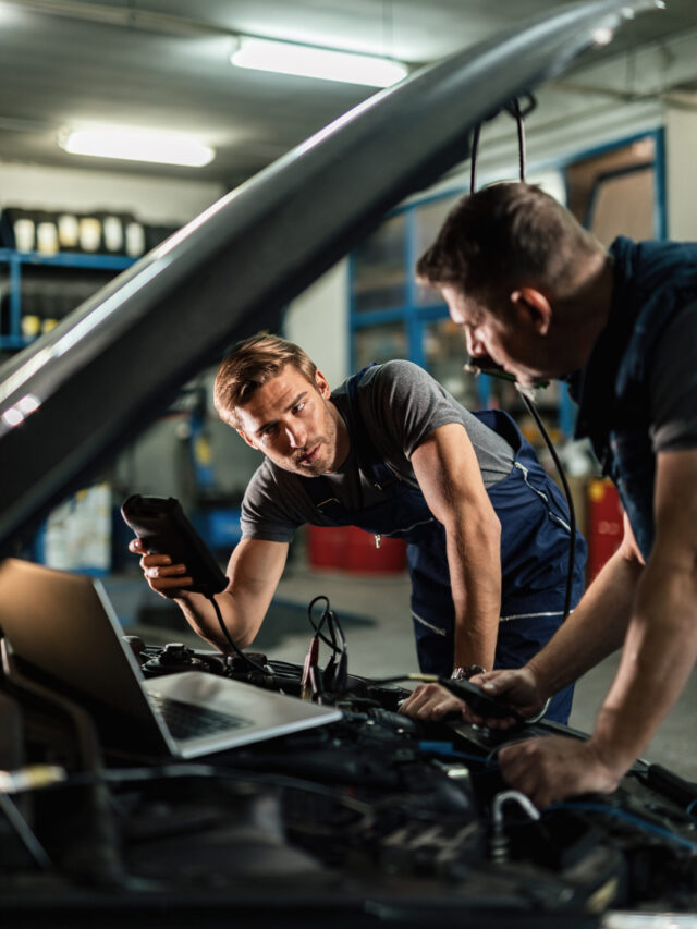 Auto mechanics using diagnostic tools while repairing car in a w