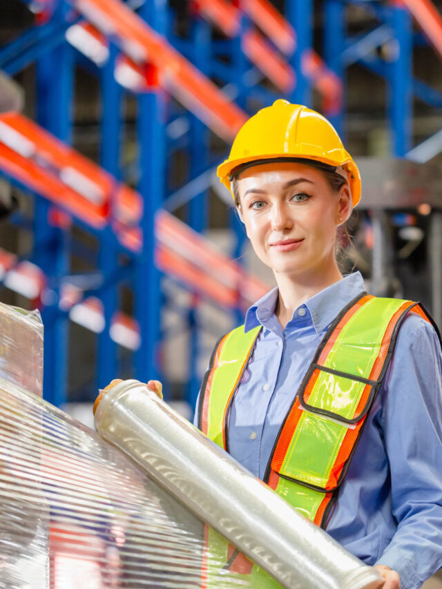 Female worker wrapping boxes in stretch film at warehouse, Worker wrapping stretch film parcel on pallet in factory warehouse