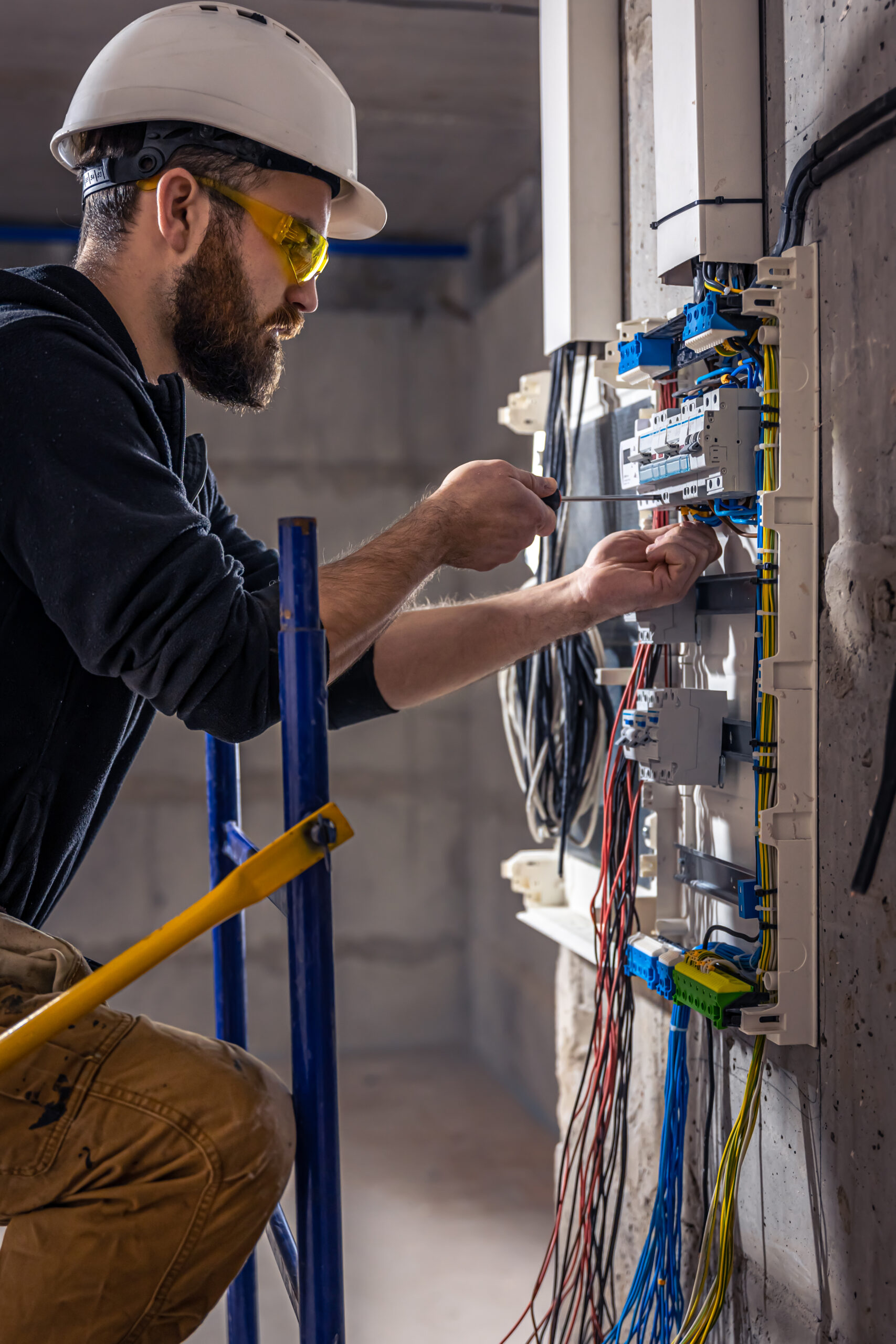 male electrician works switchboard with electrical connecting cable scaled
