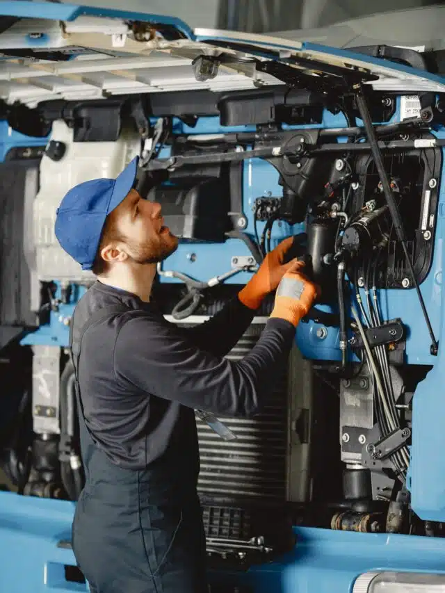 Worker checks quality of truck in garage in uniform