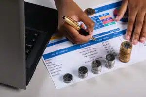 uma pessoa preenchendo uma lista de verificacao com moedas e um laptop moeda brasileira