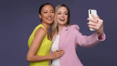 duas mulheres tirando selfie dita mulher rosa amarelo