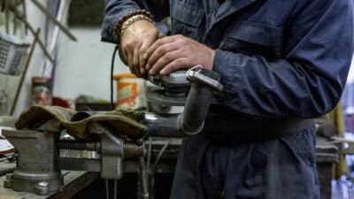 heavy industry worker cutting steel with angle grinder car service