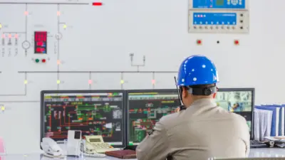 engenheiro capacete azul sala controle monitores diagramas
