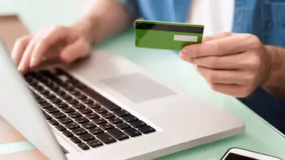 pessoa usando notebook e cartao de credito verde para pagamento online