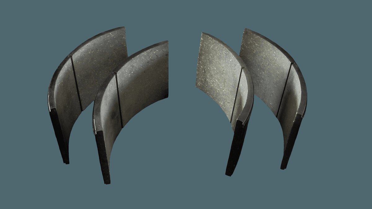 Recuperar ou trocar peça de ponte rolante: como decidir 2 Pares de lonas de freio industrial curvas, de cor escura, sobre fundo verde-acinzentado