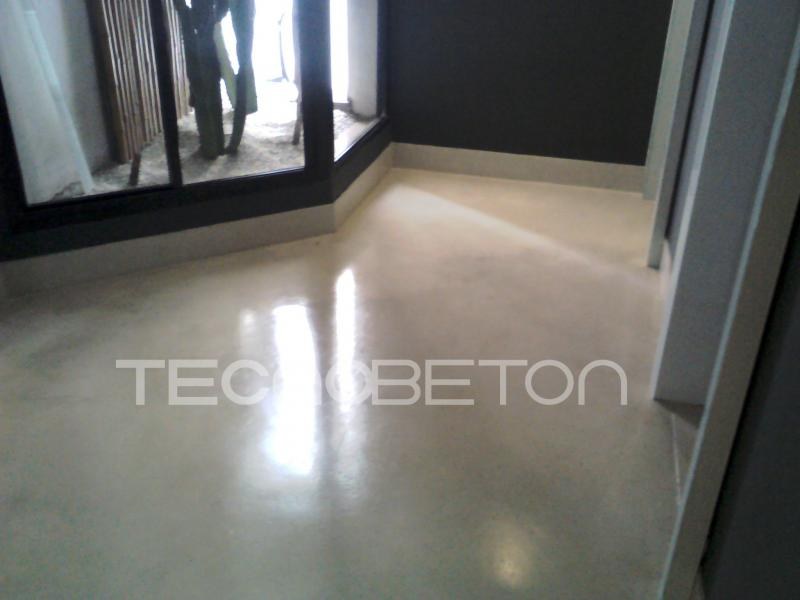 Resina para cimento queimado: tipos e como escolher 2 Piso cimentício claro com acabamento de alto brilho, refletindo a luz das janelas em uma sala comercial vazia