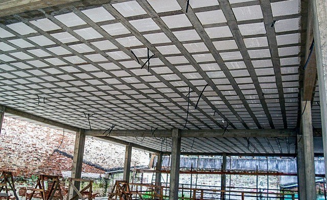 Como rebocar laje de isopor: chapisco, reboco e gesso 2 Teto de uma laje bidirecional com blocos de EPS formando um quadriculado entre nervuras de concreto, em um galpão em obra