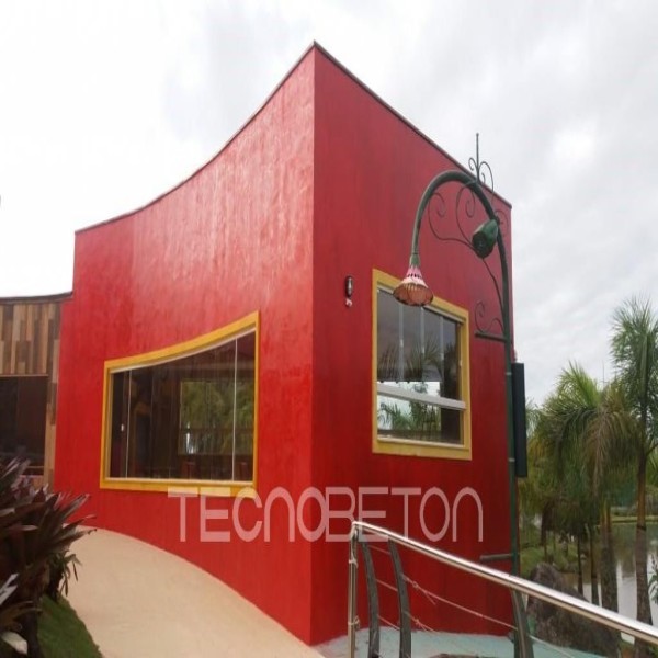 Revestimento para parede externa e muro: como escolher 3 Fachada curva de casa revestida com cimento queimado vermelho, com janelas de moldura amarela